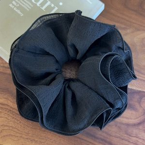 Détail d'un chouchou noir surdimensionné avec texture de crêpe plissé doux et fluide