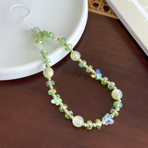 Détails de perles papillon en verre coloré et gemmes vertes sur une lanière de téléphone
