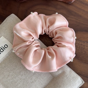Detail of pink satin hair scrunchie with delicate white pearl beads and ruffle edge