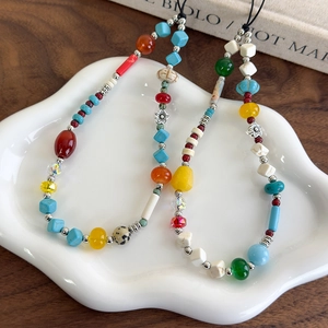 Handmade colorful stone bead phone wrist straps displayed on a white ceramic plate