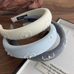Detail of three thick padded headbands with elegant pearl flower embroidery and fabric texture