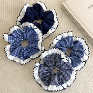 Détail de quatre chouchous en tissu à carreaux bleus avec nœuds élégants et bordures en dentelle
