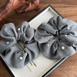Set of two gray textured fabric scrunchies with embossed rose patterns and faux pearls