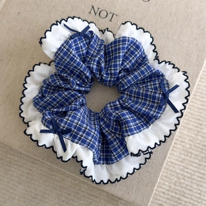 Détail d'un chouchou à carreaux bleus avec bordure en dentelle et petits nœuds