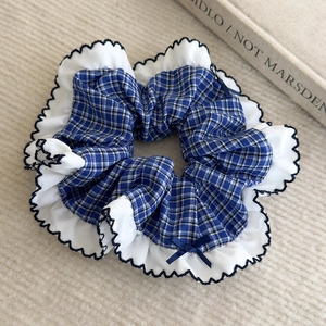 Détail du chouchou à carreaux bleus avec bords volantés blancs et petit nœud