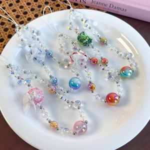 Close-up of beaded phone wrist straps with floral fabric balls and colorful resin charms
