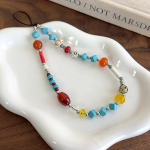 Detailed close-up of colorful beaded phone strap with blue, red and yellow beads on tray