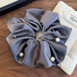 Detail of grey satin scrunchie with white faux pearls and silver beads on wood