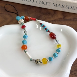 Close-up of colorful stone beaded phone strap with turquoise and agate on ceramic plate