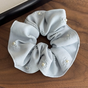 Macro detail of large blue-grey floral embossed hair scrunchie with white pearl accents