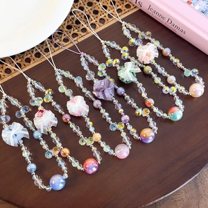 Detail of colorful beaded phone wrist straps with glass resin flowers and bows on wood