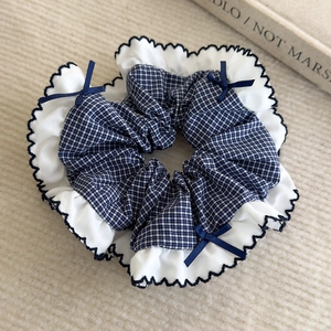 Détail du chouchou à carreaux bleus avec volants blancs et petits nœuds en soie marine