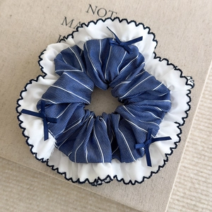 Détail du chouchou rayé bleu avec bords ondulés et petits nœuds en ruban bleu