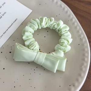 Detailed view of a mint green fabric scrunchie with bow tie on a ceramic plate