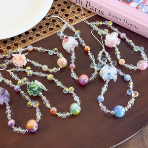 Detailed view of colorful beaded phone straps with lace flowers on a wooden table