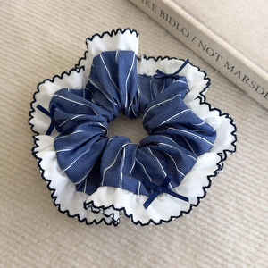 Détail du chouchou à rayures bleues avec nœuds et bords élégants en dentelle ondulée