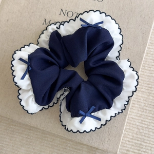 Détail de chouchou à nœud bleu marine et blanc avec bords ondulés et style preppy
