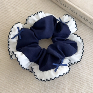 Détail d'un chouchou bleu à carreaux avec bords blancs à volants et petits nœuds