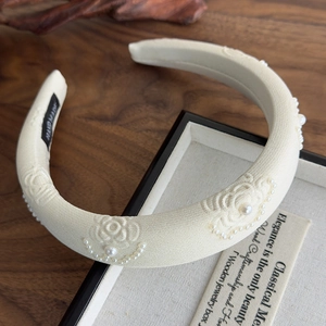 Close-up of cream handmade fabric headband with rose embroidery and pearl accents