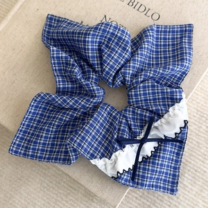 Détail du chouchou à carreaux bleus avec bordure en dentelle blanche et noeud