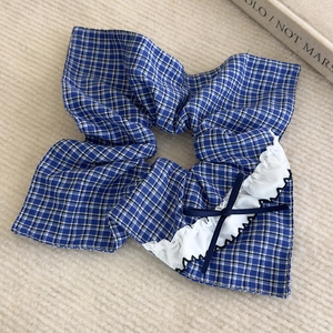 Détail d'un chouchou à carreaux bleus avec dentelle blanche et un petit nœud en ruban bleu