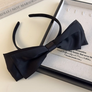 Macro view of textured black satin headband featuring a tiered 3D velvet bow detail