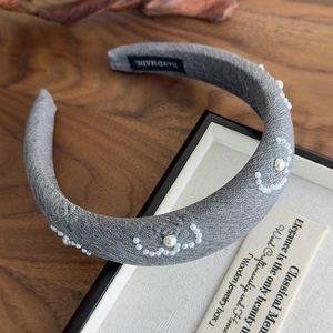 Detail of grey fabric headband with hand-sewn white pearls and hand made label