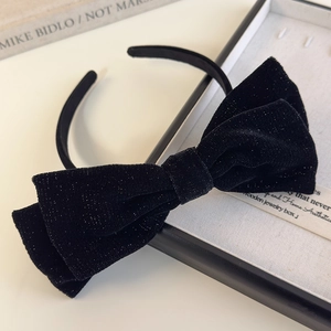 Detailed close-up of a premium black velvet bow headband with subtle glittering texture