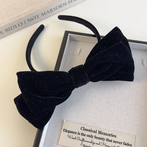 Detail view of a vintage black velvet bow headband with glitter in an elegant gift box