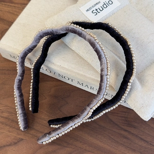 Detail of elegant flocked headbands with gold bead trim in grey and black velvet textures
