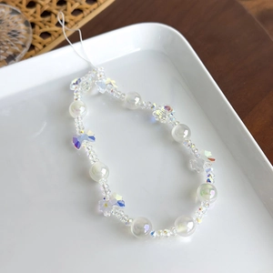 Gros plan sur une dragonne de téléphone en perles de cristal avec breloque papillon