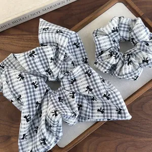 Chouchou à carreaux bleus avec nœud et motif vichy disposé sur un plateau en bois