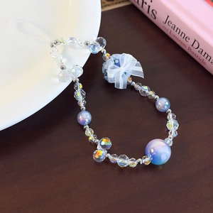 Detail of beaded phone wristlet with light blue flowers and lace bow on a wooden table
