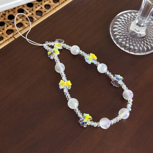 Détail de la dragonne de téléphone en perles blanches et d'un pendentif papillon jaune irisé