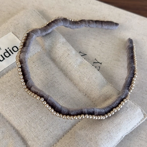 Detailed view of grey-purple velvet wavy headband with elegant pearl trim detailing