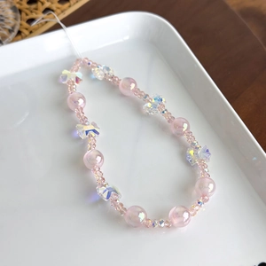 Détail d'une dragonne de téléphone en perles irisées roses avec nœud coloré chic