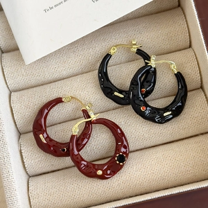 Detail view of retro red and black enamel drop earrings in a beige jewelry box tray