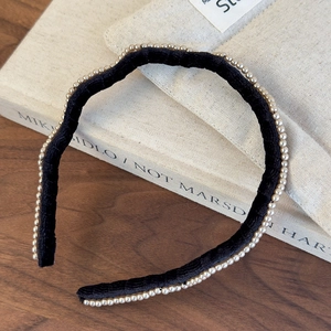 Close-up of elegant black velvet headband with white pearl trim on a vintage book
