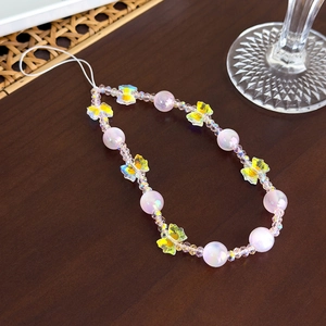 Détail du bijou de téléphone perlé avec perles violettes et nœuds en résine jaune