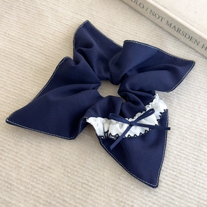Détail d'un chouchou bleu à carreaux avec dentelle blanche et petit nœud élégant