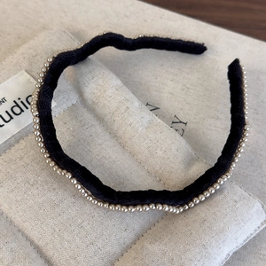 Detailed view of the black velvet headband featuring elegant champagne pearl embellishments
