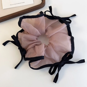 Λεπτομέρεια ροζ scrunchie από πλέγμα με μαύρο τελείωμα και φιόγκους σε λευκή επιφάνεια
