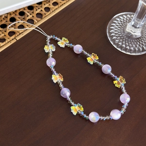 Détail de la lanière de téléphone perlée avec perles violettes et breloque papillon