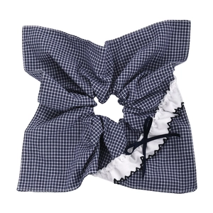 Détail d'un chouchou à carreaux bleus avec bordure en dentelle et nœud élégant