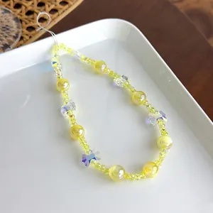 Gros plan d'une dragonne de téléphone en perles jaunes avec des breloques papillon