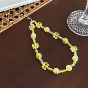 Vue détaillée des perles papillon jaunes et des breloques en cristal sur la sangle de mobile