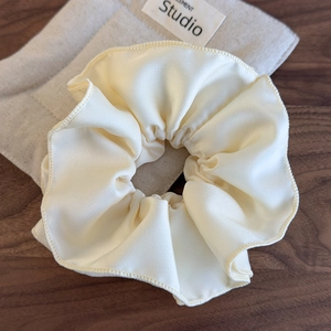 Close-up of cream-colored oversized satin scrunchie showing fine stitching and soft texture