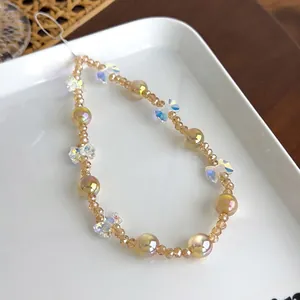 Détail macro de perles en verre ambré et pendentif papillon irisé sur dragonne