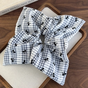 Détail d'un chouchou à carreaux noir et blanc avec motifs nœuds sur plateau bois