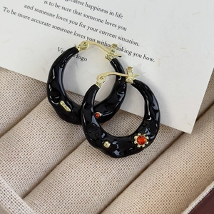 Detailed macro view of vintage irregular wavy black enamel hoop earrings with gold accents